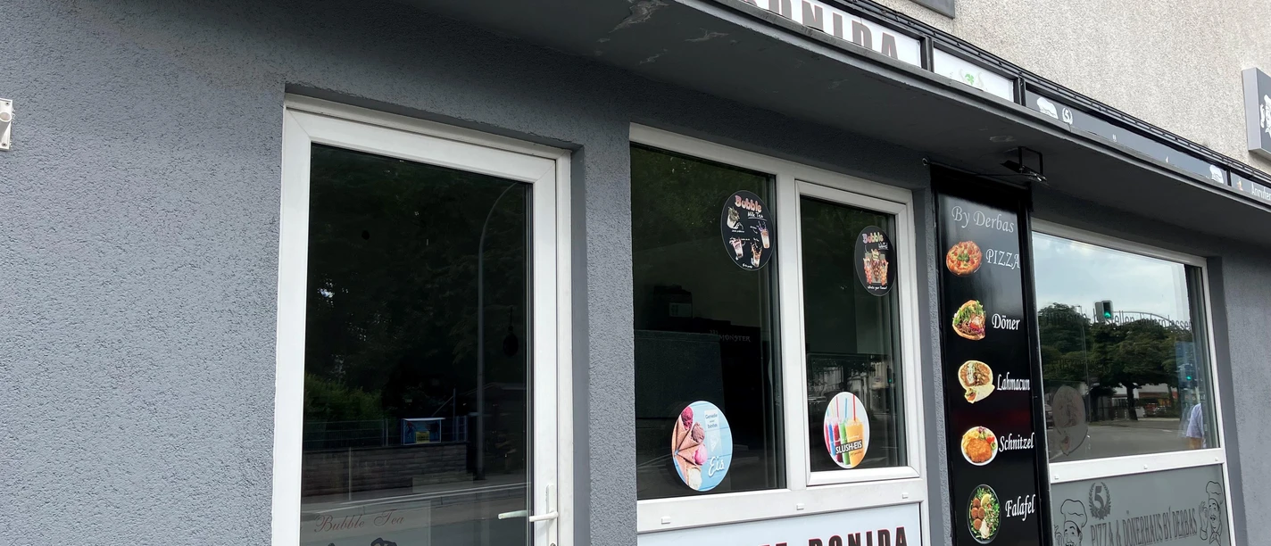 Eingang und Fensterfront des Eiscafé Ronida mit Eis-, Bubble-Tea- und Snackwerbung