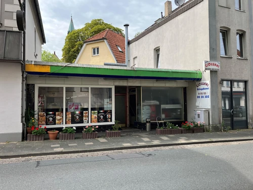 Außenansicht von Giovanni's Pizza Grill mit Schaufenstern, Blumenkästen und Beschilderung