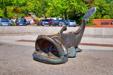 wels-sonnenschein Bronzeskulptur des Riesenwelses mit aufgerissenem Maul auf dem Marktplatz in Bad Zwischenahn.