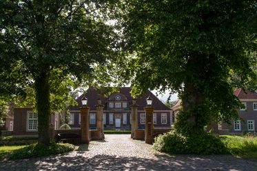 Schloss Herzford Backsteinernes Herrenhaus mit Toranlagen und altem Baumbestand im Sonnenschein von Lingen.