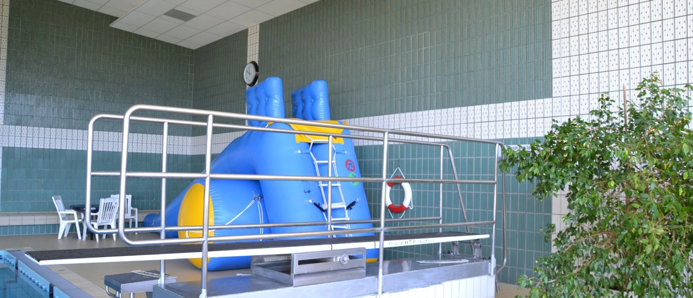 Hallenbad Werlte Innenbereich des Hallenbads mit Sprungbrett, blauem Spielgerät und Sitzbereich am Beckenrand