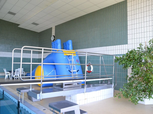 Hallenbad Werlte Innenbereich des Hallenbads mit Sprungbrett, blauem Spielgerät und Sitzbereich am Beckenrand