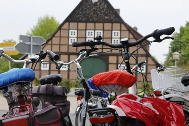 Rad & Roller Mehrere abgestellte Fahrräder vor einem traditionellen Fachwerkhaus in ländlicher Umgebung.