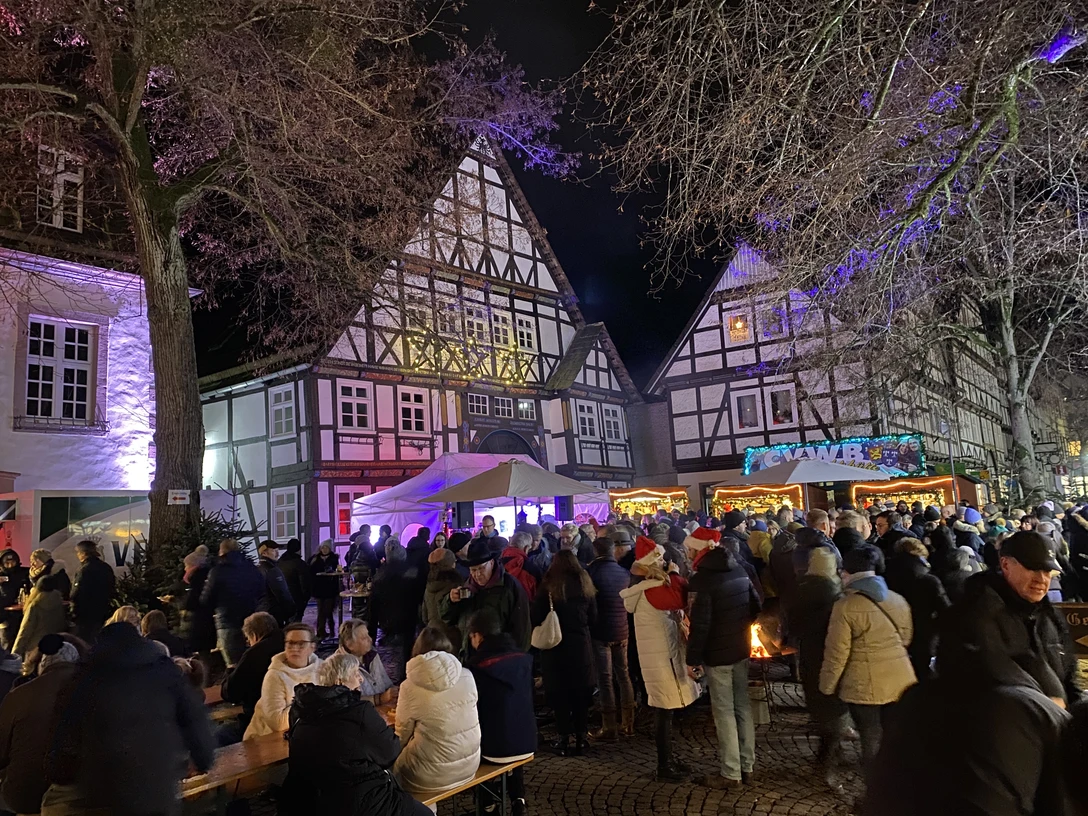 Sternenmarkt in Beverungen Historische Fachwerkhäuser erleuchten im Abendlicht bei einem belebten Weihnachtsmarkt in Beverungen.