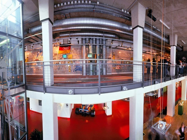 Deutsches Sport & Olympia Museum Panoramablick im Inneren des Sportmuseums mit moderner Architektur, farbenfrohem Boden und Ausstellungsstücken.