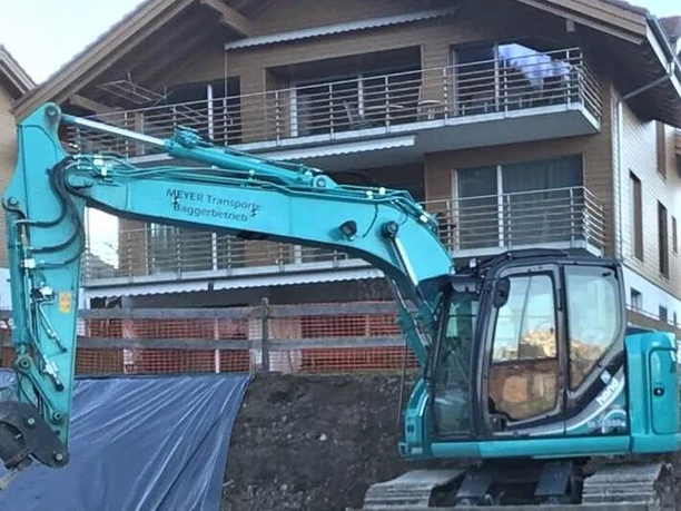 Bagger vor Mehrfamilienhaus
