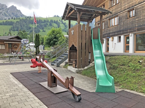 Playground with seesaw and slide Children's playground with green slide and seesaw