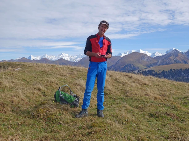 A man in hiking clothes is standing in an alpine meadow