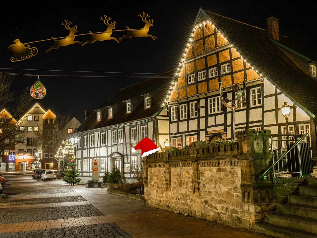 Weihnachtlich geschmückte Fachwerkhäuser erleuchten abends eine historische Straßenzeile.