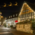Stadtführung_Weihnachten Weihnachtlich geschmückte Fachwerkhäuser erleuchten abends eine historische Straßenzeile.