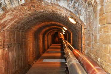 Unterirdischer Solegang in Bad Rothenfelde Backstein-Gewölbetunnel mit Röhren und schwacher Beleuchtung entlang des Weges.