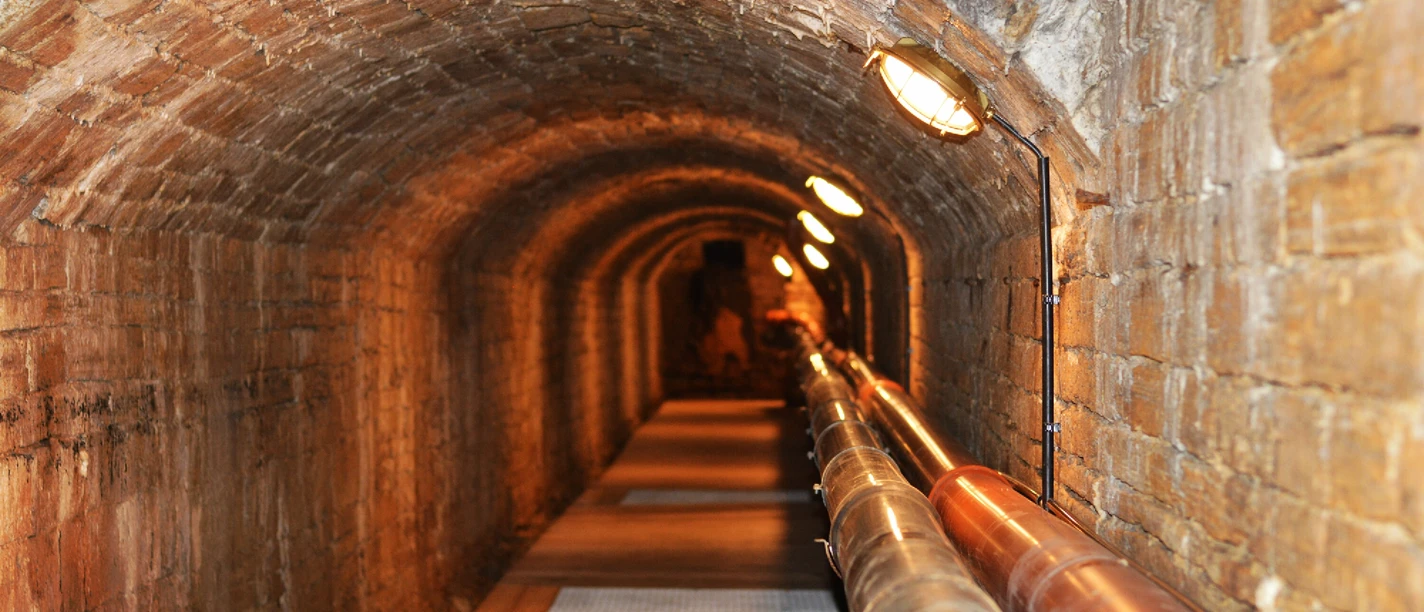 Unterirdischer Solegang in Bad Rothenfelde Backstein-Gewölbetunnel mit Röhren und schwacher Beleuchtung entlang des Weges.