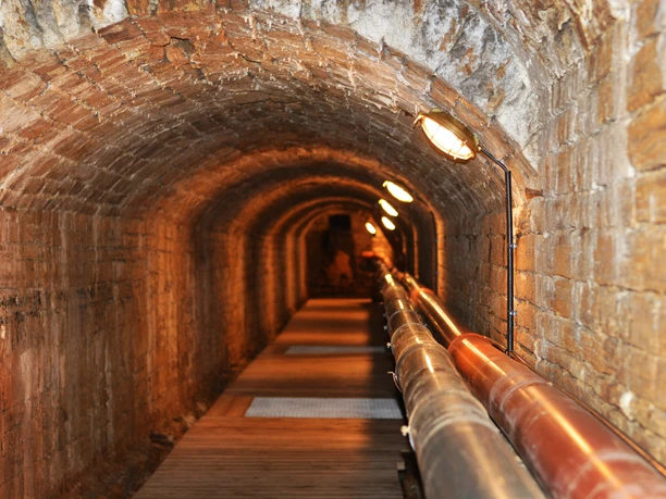Unterirdischer Solegang in Bad Rothenfelde Backstein-Gewölbetunnel mit Röhren und schwacher Beleuchtung entlang des Weges.