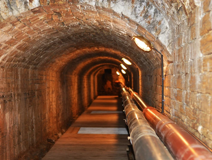 Unterirdischer Solegang in Bad Rothenfelde Zout water stroomt door de ondergrondse gang van de bron naar de gradeerwerken in Bad RothenfeldeBackstein-Gewölbetunnel mit Röhren und schwacher Beleuchtung entlang des Weges.Brick vaulted tunnel with tubes and dim lighting along the path.Muret hvælvet tunnel med rør og dæmpet belysning langs stien.