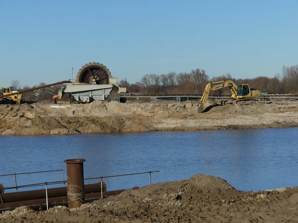 Trenn- und Förderanlage für Sand-Wasser-Gemisch Eine Industrielandschaft mit einem großen Rad für die Trennung von Sand-Wasser-Gemischen am Ufer.