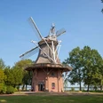 windmühle im kurpark Eine historische Windmühle im Kurpark, umgeben von grüner Natur und Bäumen, unter strahlend blauem Himmel.