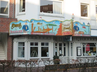 bruns-fassade Fassade der Aalräucherei Bruns mit buntem, maritim bemaltem Schild über den weißen Ladenfenstern.