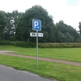 Wohnmobilstellplatz Hengstforde Das Bild zeigt einen Wohnmobilstellplatz, umgeben von grünen Wiesen und Bäumen. Ein Schild mit einem „P“ weist auf die Parkmöglichkeit hin und ein Weg führt durch die Landschaft.