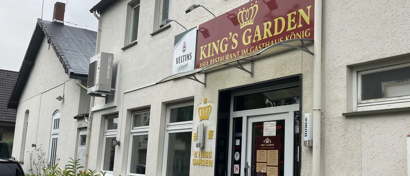 Eingang des Asia-Restaurants King’s Garden mit rotem Schild an heller Hausfassade
