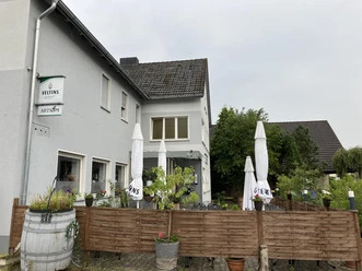 Außenansicht des Restaurant Artiom mit Terrasse, Sonnenschirmen und Holzabtrennung