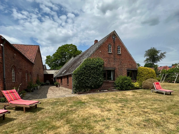 Im Garten View of the farmhouse from the spacious garden with climbing frame for children and sun loungers for adults.