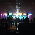 Bowlingcente Werlte Menschen beim Bowling in beleuchtetem Bowlingcenter mit Bildschirmen und farbigen Lichtern.