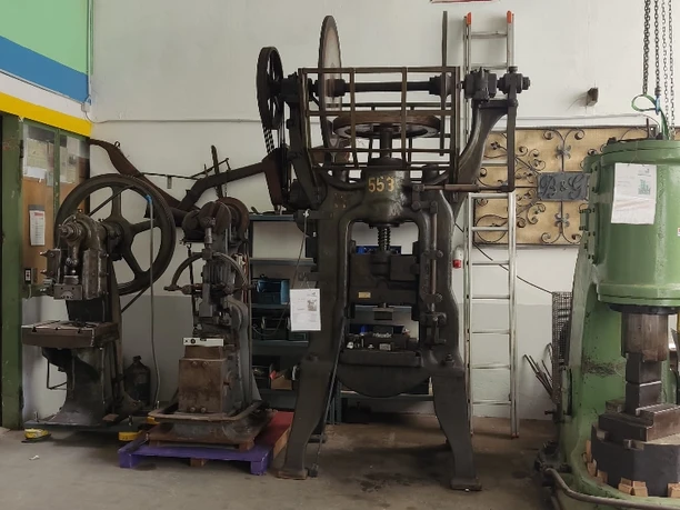 Die Krachmacher im Eingangsbereich v. links= Excenterpresse/Schwinghammer/Reib-Spindelpresse/Bêché-Hammer Historische Maschinen und Pressen in einer Werkstatt, darunter ein älteres Modell mit massiven Zahnrädern.
