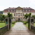 Historisches Herrenhaus mit symmetrischer Fassade, umgeben von gepflegtem Garten und Kiesweg.
