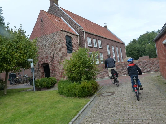 Ev.-ref. Kirche Hamswehrum 2 Radfahrer fahren auf die Kirche in Hamswehrum zu.