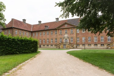 Kloster Clarholz mit Blick auf den Eingang Backsteinernes Herrenhaus mit roten Ziegeln, symmetrische Fassade, vor einem gepflegten Gartenweg.