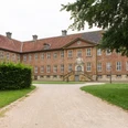 Kloster Clarholz mit Blick auf den Eingang Backsteinernes Herrenhaus mit roten Ziegeln, symmetrische Fassade, vor einem gepflegten Gartenweg.