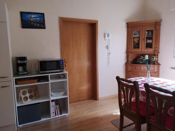 Essbereich, FeWo Krauß Heller Essbereich mit Holzboden, Holztisch und Stühlen, schlichter Dekoration und Blick auf Schrank.