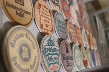 Een verzameling ronde bierviltjes met verschillende brouwerijlabels en kleuren, waaronder Radeberger Pilsner en Wörlitzer Bier.