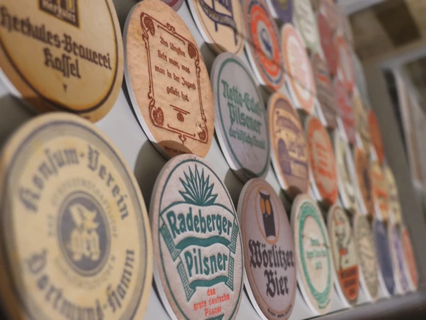 Een verzameling ronde bierviltjes met verschillende brouwerijlabels en kleuren, waaronder Radeberger Pilsner en Wörlitzer Bier.