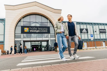 Halle Leipzig The Style Outlets - Shopping in Leipzig Ein Paar verlässt lachend und mit Einkaufstüten in der Hand das Halle Leipzig The Style Outlets Center, Shopping, Einkaufen, Freizeit, Familie, Ausflug