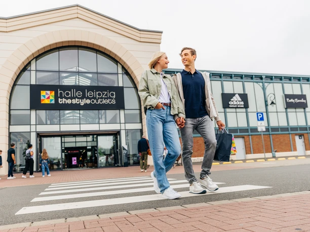 Un couple quitte le Halle Leipzig The Style Outlets Center en riant et en tenant des sacs de shopping à la main, shopping, loisirs, famille, excursion