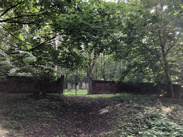 Jüdischer Friedhof Eingebettet in dichte Bäume, liegt der historische jüdische Friedhof mit seinem geschlossenen Gittertor.