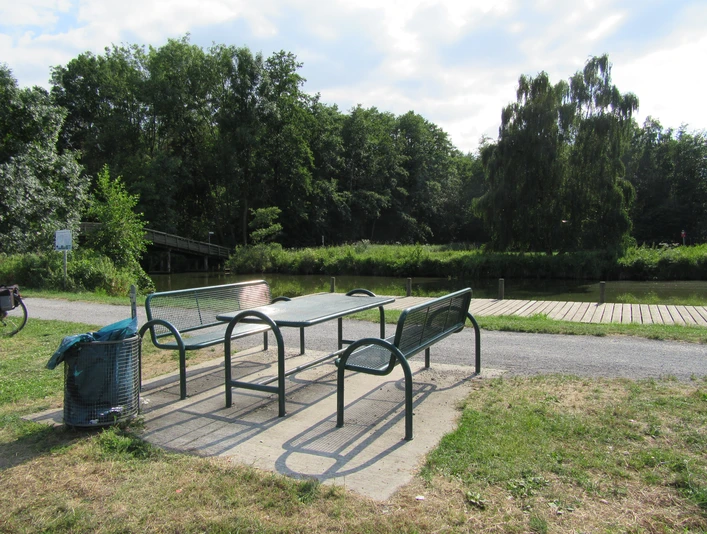 Ein Picknicktisch steht an einem gepflegten Uferweg, umgeben von Bäumen und dem Hagenburger Kanal.