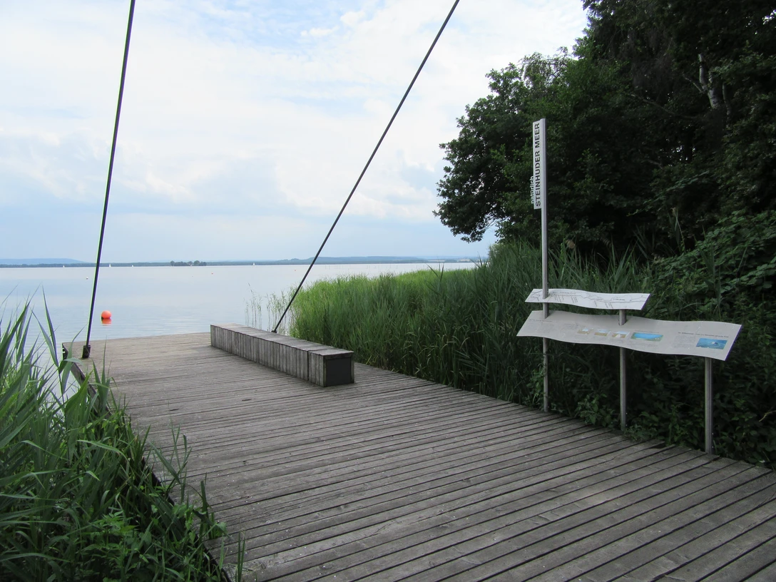 Picknickplatz Sehbrücke Mardorf Holzterrasse mit Bank am Steinhuder Meer, umgeben von Schilf, mit Blick auf das Wasser.