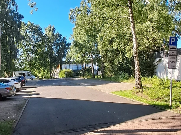 Ein ruhiger Parkplatz umgeben von hohen Bäumen an einer klaren, sonnigen Himmelstag.