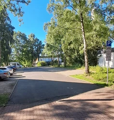 Parkplatz Meerstraße Ein ruhiger Parkplatz umgeben von hohen Bäumen an einer klaren, sonnigen Himmelstag.