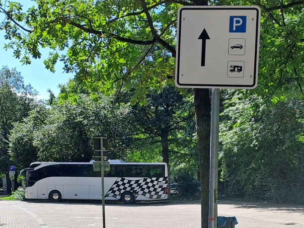 Beschilderung eines Parkplatzes mit Bus- und Wohnmobilabstellfläche nahe bewaldeter Umgebung.