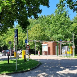 Parkplatz Bruchdamm Kassenautomat Kassenautomat am Parkplatz Bruchdamm, umgeben von Bäumen und parkenden Autos bei sonnigem Wetter.