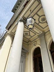 Portikus am Palais Rastede mit Säulen, Hängelaterne und verziertem Eingangsbereich.