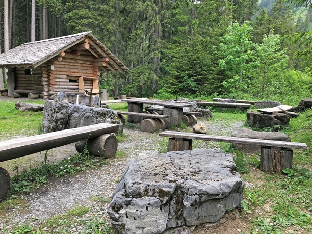 Feuerstelle mit Sitzgelegenheiten und Rundholzhütte