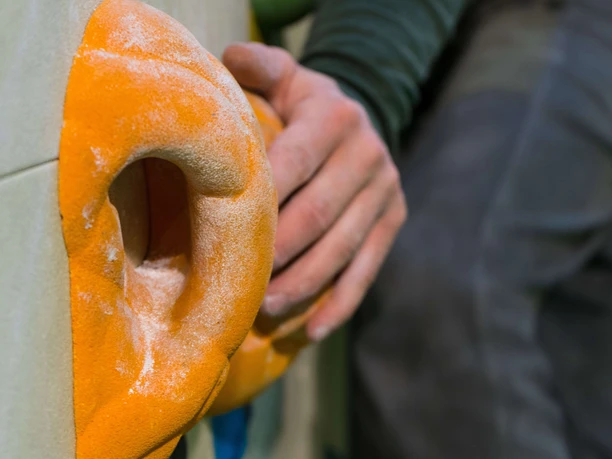 Climbing wall ideal for groups Hand reaches for yellow climbing hold