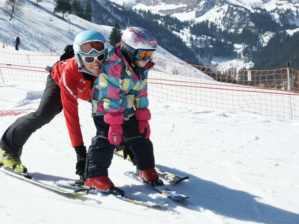 The ski instructor shows her pupil how to brake