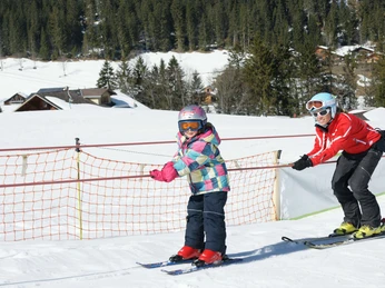 Bientôt, les élèves skieurs prennent presque seuls le téléski à corde Kind lässt sich vom Schlepplift hochziehen, die Skilehrerin ist hinter ihmChild is pulled up by the tow lift, the ski instructor is behind himL'enfant se laisse hisser par le téléski, la monitrice de ski est derrière lui