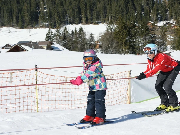 Soon the ski students are riding the rope lift almost alone Child is pulled up by the tow lift, the ski instructor is behind him