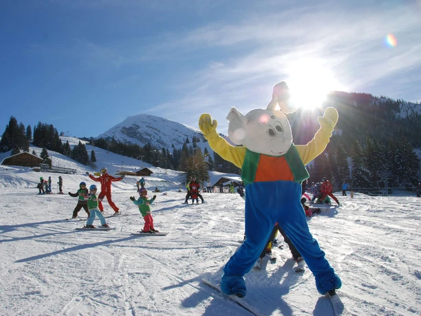 With Snowli in the snow The mascot Snowli is skiing in front of a group of children